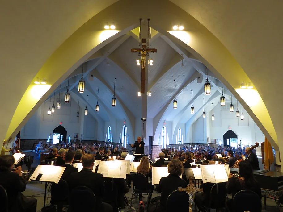 wide view of music director conducting orchestra in Ave Maria parish