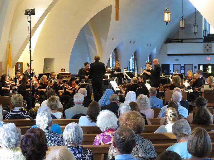 people sitting in pews watching orchestra performance