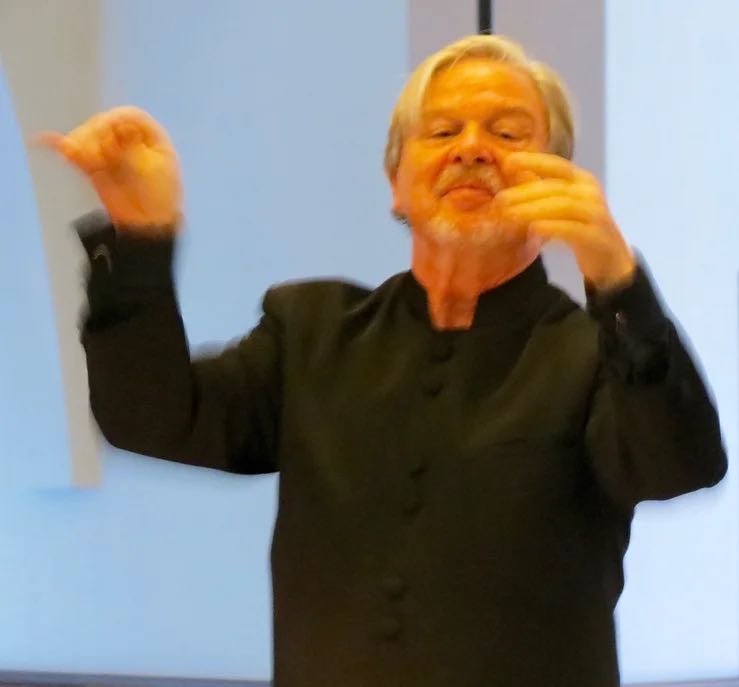 orchestra conductor with arms up in motion