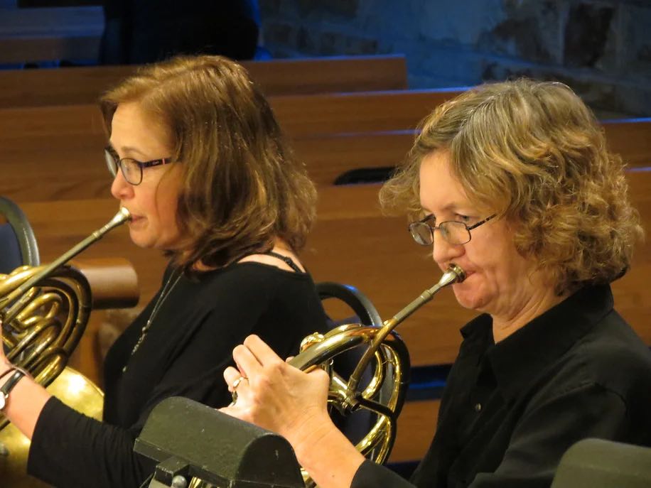 closeup of two women playing french horns