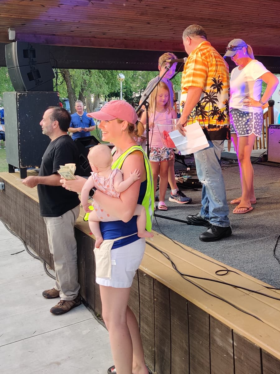 volunteers giving out raffle prizes at the stage during Music in the Park