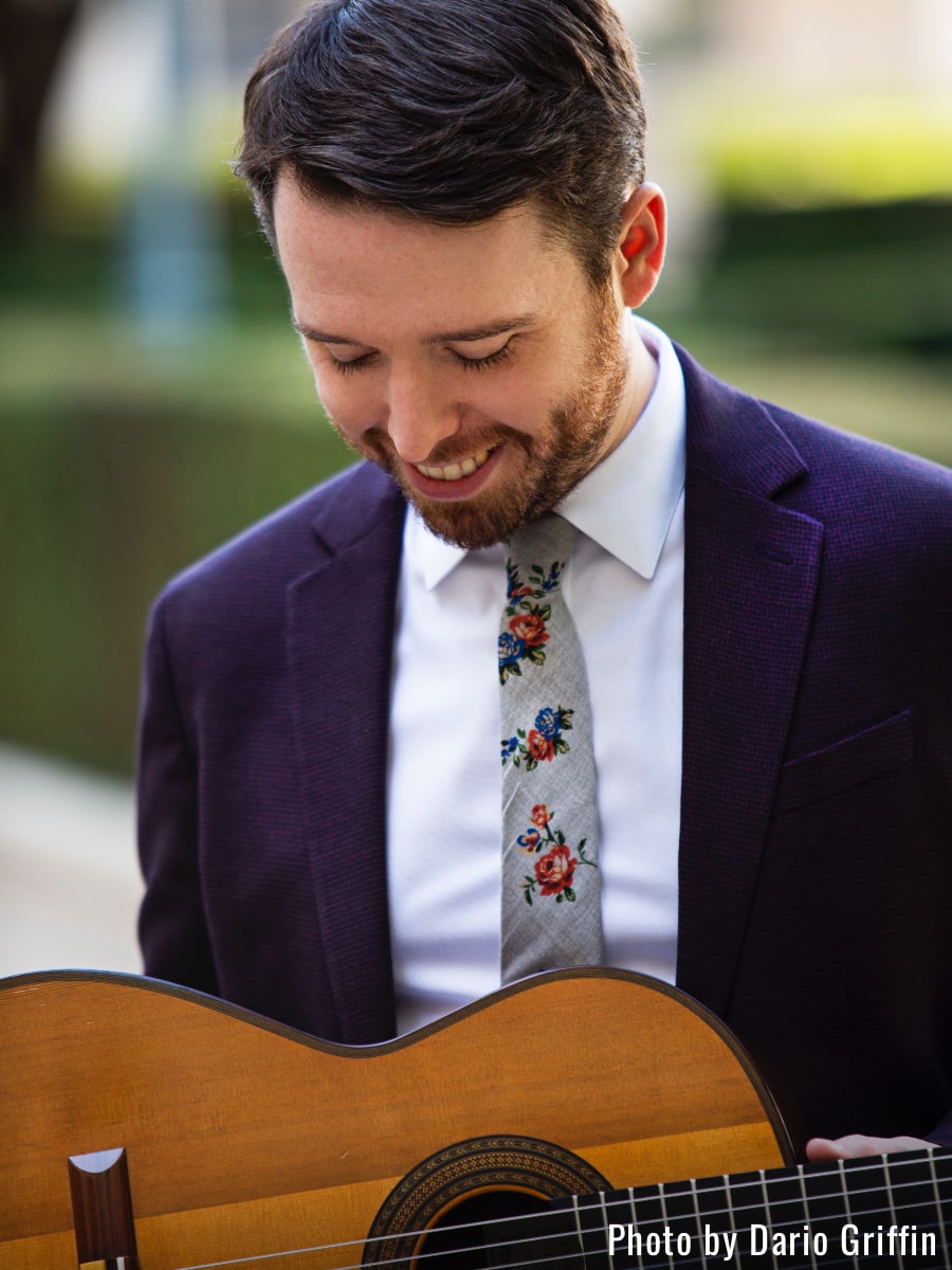 Musician Colin Davin smiling while looking down at his guitar; photo courtesy Dario Griffin